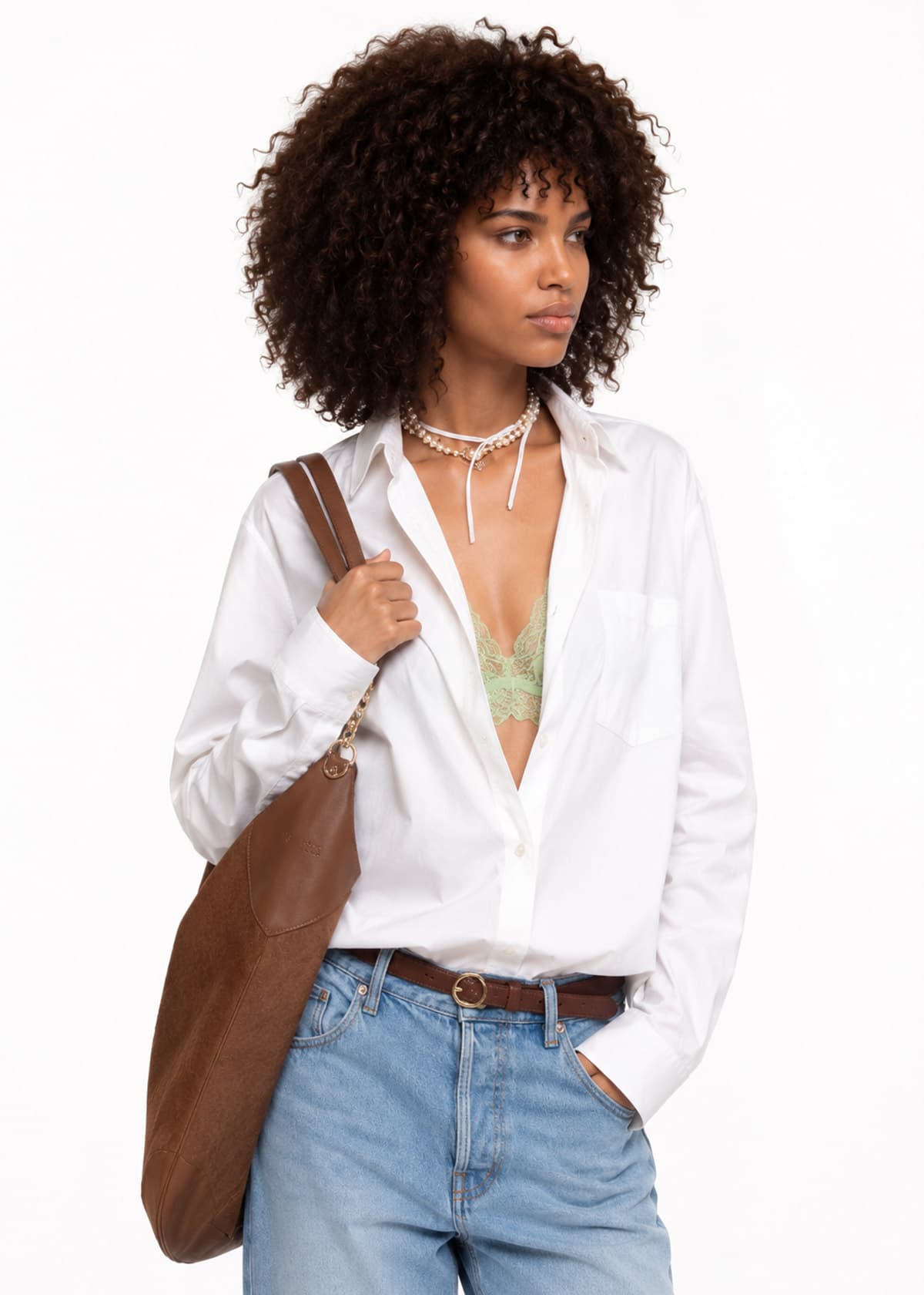 Capo indossato da un talento AI: camicia bianca aperta con collana di perle e borsa in pelle marrone.