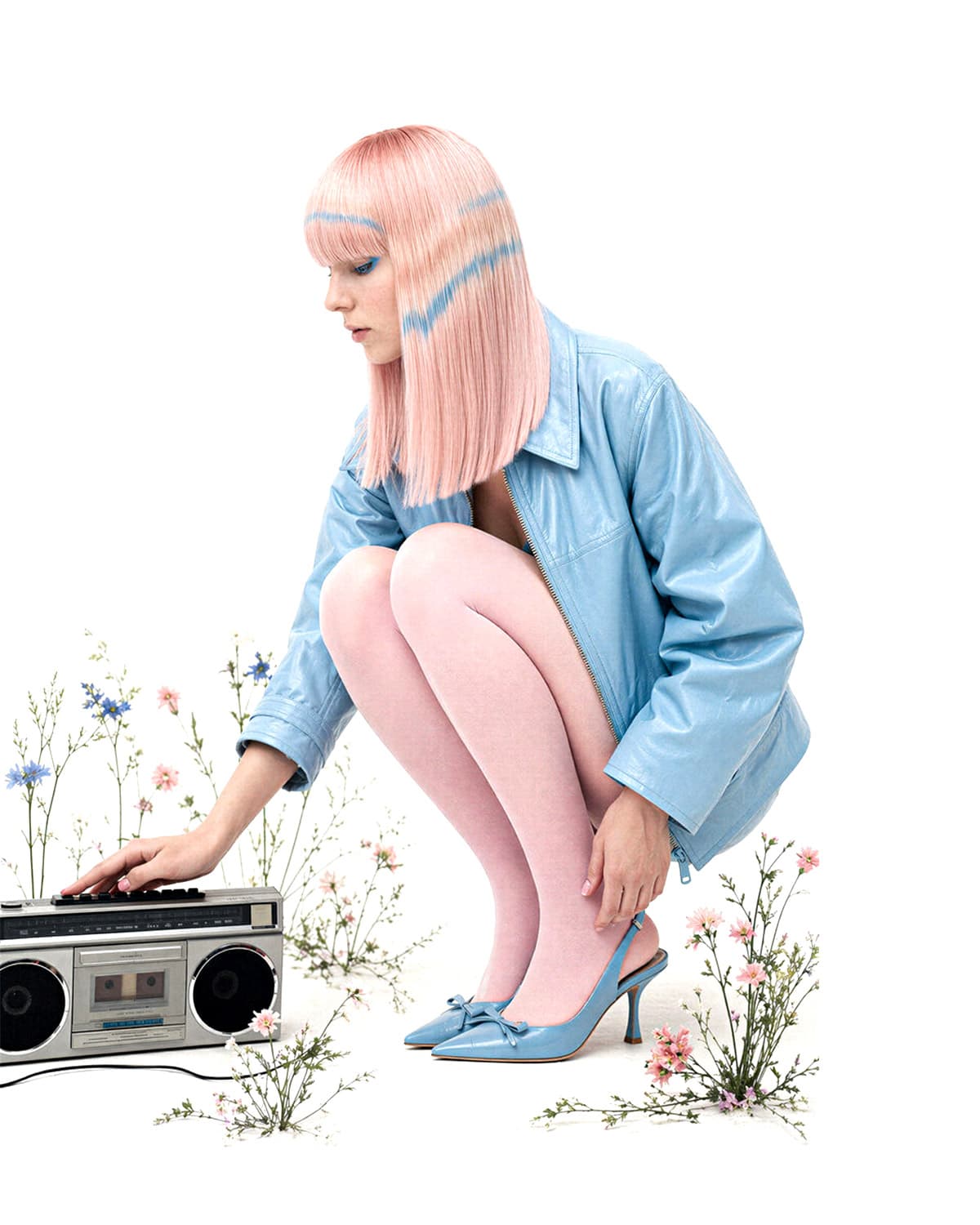 Editoriale generato con AI: modella dai capelli rosa accovacciata in giacca azzurra e collant rosa, tra fiori di campo su fondo bianco.