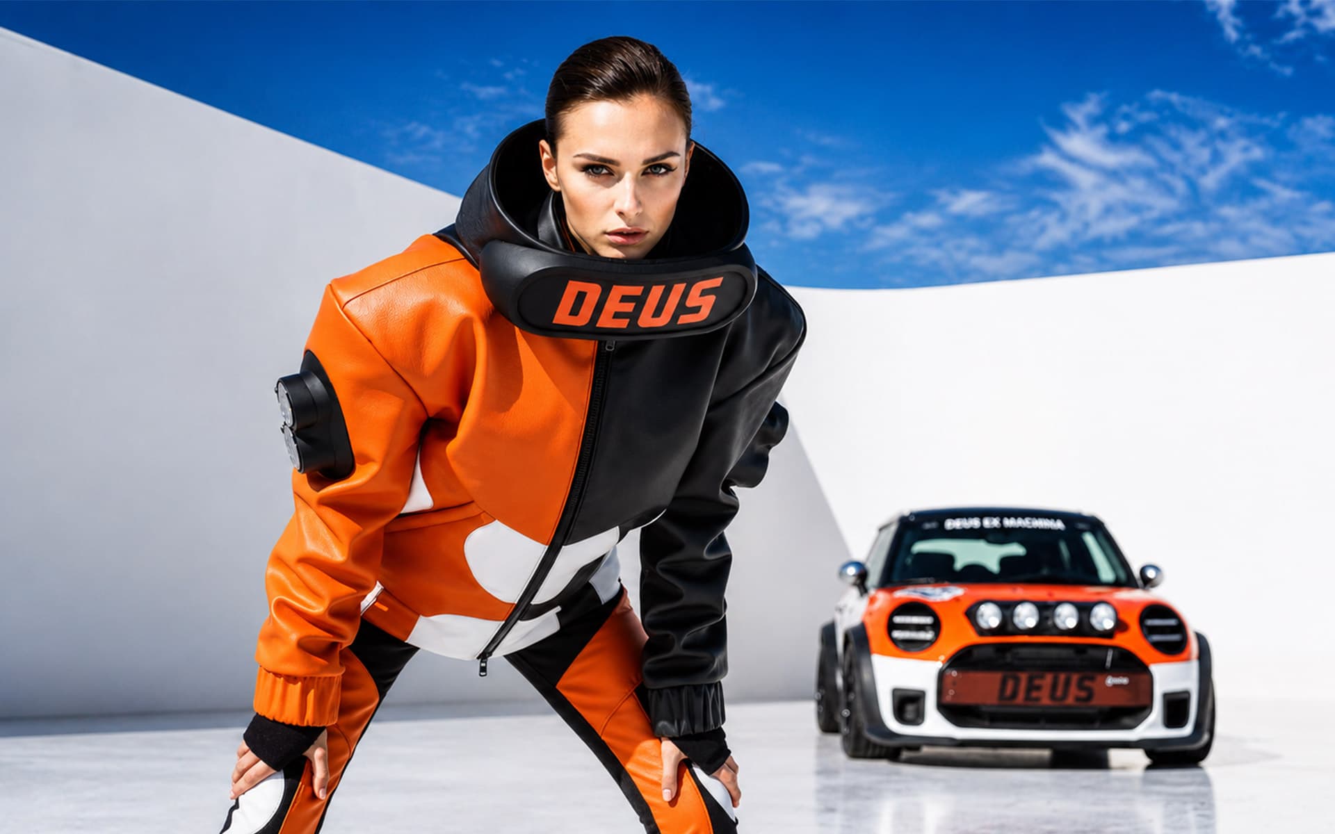 Produzione moda con AI: modella in giacca da moto arancione e nera accovacciata accanto a una hot hatch da rally, in uno studio bianco.